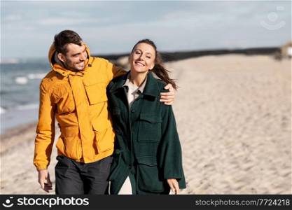 love, relationship and people concept - happy couple walking along autumn beach. couple walking along autumn beach