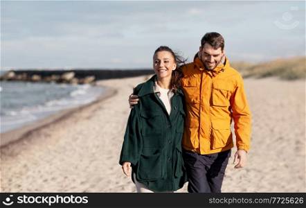 love, relationship and people concept - happy couple walking along autumn beach. couple walking along autumn beach