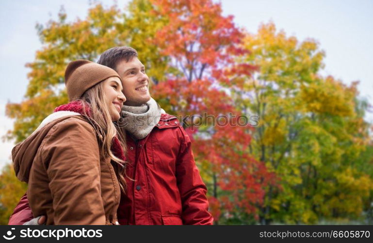 love, relationship and season concept - happy teenage couple hugging over autumn park background. happy teenage couple hugging in autumn park