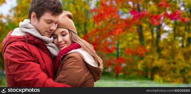 love, relationship and season concept - happy teenage couple hugging over autumn park background. happy teenage couple hugging in autumn park