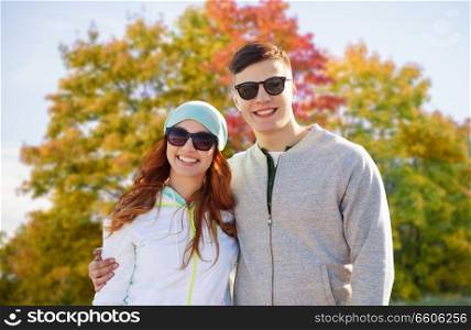 love, relationship and season concept - happy teenage couple over autumn park background. happy teenage couple in autumn park