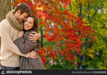 love, relationship and season concept - smiling couple hugging over autumn park background. smiling couple hugging in autumn park