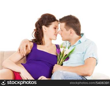 love, relationship, anniversary concept - happy expecting parents with flowers at home