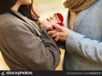 love, relationship, family and people concept - close up of couple with red gift box in autumn park