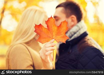love, relationship, family and people concept - close up of couple with maple leaf kissing in autumn park