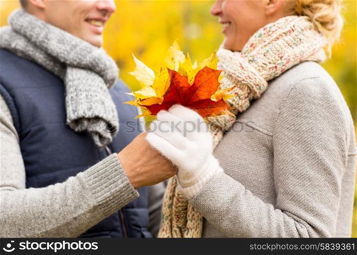 love, relationship, family and people concept - close up of happy smiling couple with maple leaves in autumn park