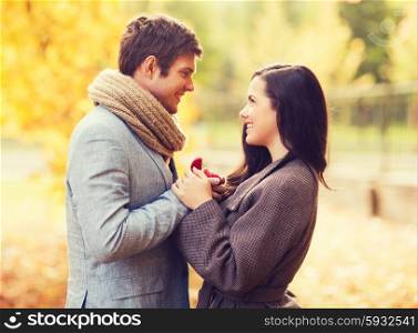 love, relationship, family and people concept - close up of smiling couple with red gift box in autumn park