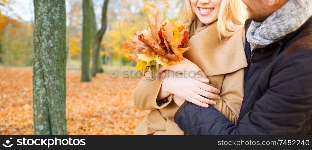 love, relationship, family and people concept - close up of smiling couple with bunch of leaves hugging in autumn park. close up of smiling couple hugging in autumn park