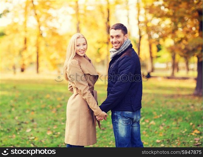 love, relationship, family and people concept - smiling couple holding hands in autumn park