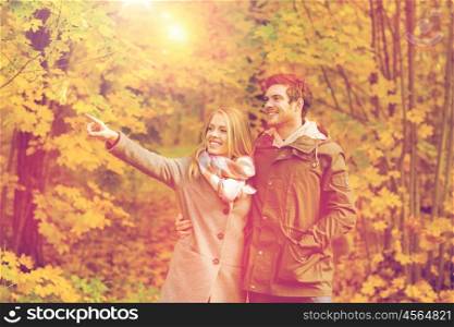 love, relationship, family and people concept - smiling couple hugging and pointing finger in autumn park