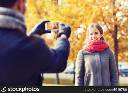 love, relationship, family and people concept - smiling couple hugging and taking selfie with smartphone in autumn park