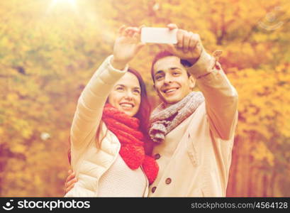 love, relationship, family and people concept - smiling couple hugging and taking selfie in autumn park