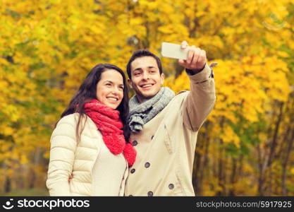 love, relationship, family and people concept - smiling couple hugging and taking selfie in autumn park