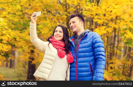 love, relationship, family and people concept - smiling couple hugging and taking selfie in autumn park