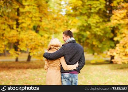 love, relationship, family and people concept - smiling couple hugging in autumn park from back