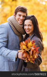 love, relationship, family and people concept - smiling couple with bunch of leaves hugging in autumn park