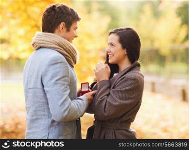 love, relationship, family and people concept - smiling couple with red gift box in autumn park