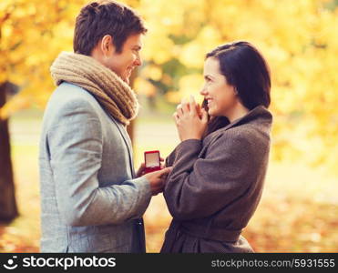 love, relationship, family and people concept - smiling couple with red gift box in autumn park