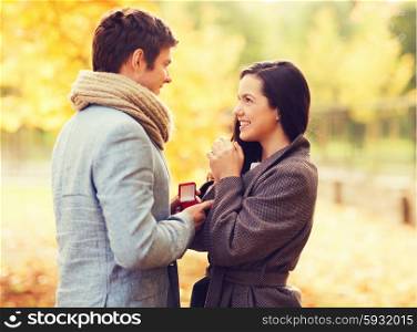 love, relationship, family and people concept - smiling couple with red gift box in autumn park