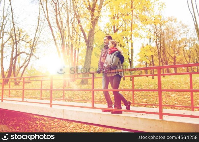 love, relationship, family, season and people concept - smiling couple hugging on bridge in autumn park