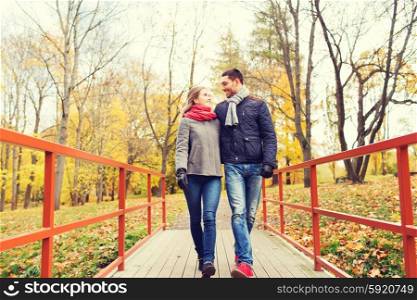 love, relationship, family, season and people concept - smiling couple hugging on bridge in autumn park