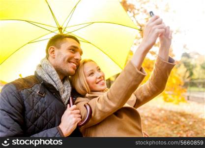 love, relationship, family, technology and people concept - smiling couple making selfie in autumn park