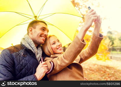 love, relationship, family, technology and people concept - smiling couple making selfie in autumn park