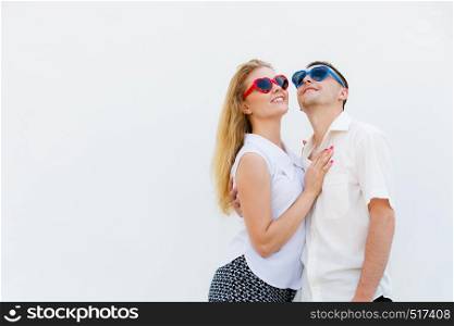Love, relationship goals, funny accessories concept. Man and woman wearing heart shape sunglasses looking happy.. Man and woman wearing heart shape sunglasses