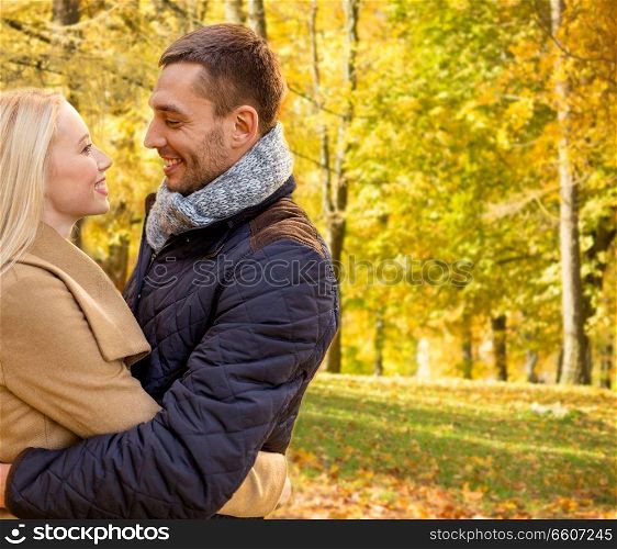 love, relationship, season and people concept - smiling couple hugging in autumn park. smiling couple hugging in autumn park