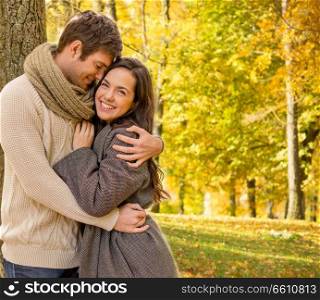 love, relationship, season and people concept - smiling couple hugging in autumn park. smiling couple hugging in autumn park