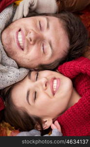 love, relationship, season, family and people concept - close up of happy smiling couple lying on autumn leaves