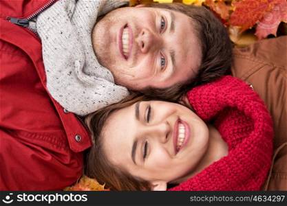 love, relationship, season, family and people concept - close up of happy smiling couple lying on autumn leaves
