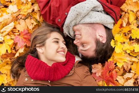 love, relationship, season, family and people concept - close up of smiling couple lying on autumn leaves