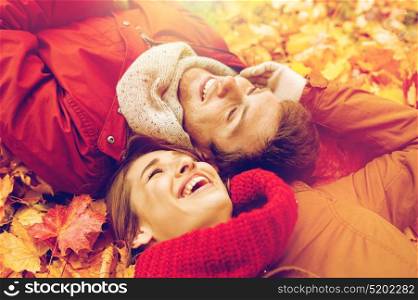 love, relationship, season, family and people concept - close up of smiling couple lying on autumn leaves. close up of smiling couple lying on autumn leaves