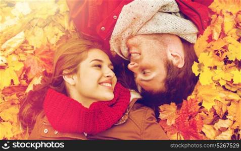 love, relationship, season, family and people concept - close up of smiling couple lying on autumn leaves. close up of smiling couple lying on autumn leaves