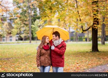 love, relationship, season, family and people concept - happy couple with umbrella walking in autumn park