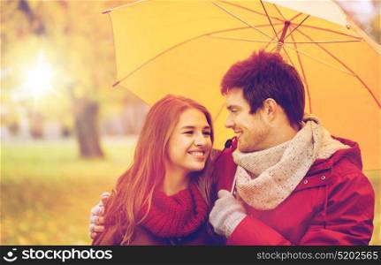 love, relationship, season, family and people concept - happy couple with umbrella walking in autumn park. smiling couple with umbrella in autumn park