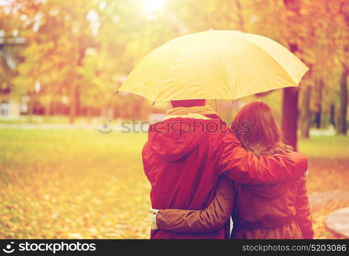 love, relationship, season, family and people concept - happy couple with umbrella walking in autumn park. happy couple with umbrella walking in autumn park