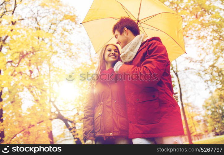 love, relationship, season, family and people concept - happy couple with umbrella walking in autumn park. smiling couple with umbrella in autumn park