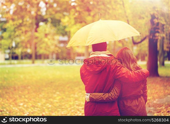 love, relationship, season, family and people concept - happy couple with umbrella walking in autumn park. happy couple with umbrella walking in autumn park