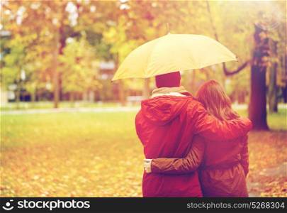 love, relationship, season, family and people concept - happy couple with umbrella walking in autumn park. happy couple with umbrella walking in autumn park