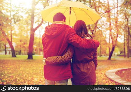 love, relationship, season, family and people concept - happy couple with umbrella walking in autumn park. happy couple with umbrella walking in autumn park