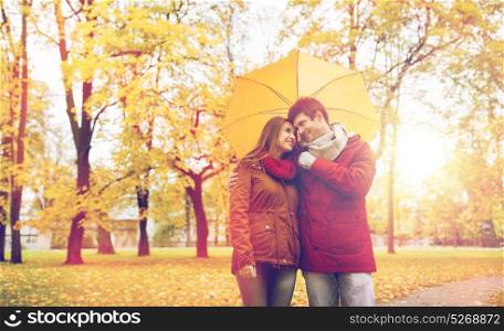love, relationship, season, family and people concept - happy couple with umbrella walking in autumn park. smiling couple with umbrella in autumn park