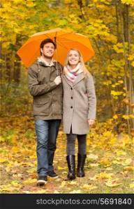 love, relationship, season, family and people concept - smiling couple with umbrella walking in autumn park