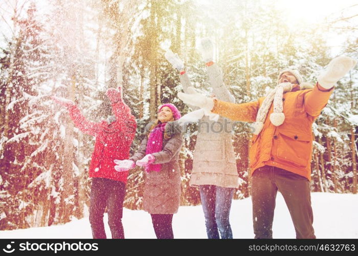 love, relationship, season, friendship and people concept - group of smiling men and women having fun and playing with snow in winter forest