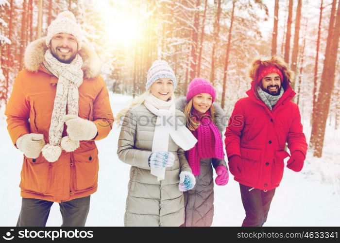 love, relationship, season, friendship and people concept - group of smiling men and women running in winter forest