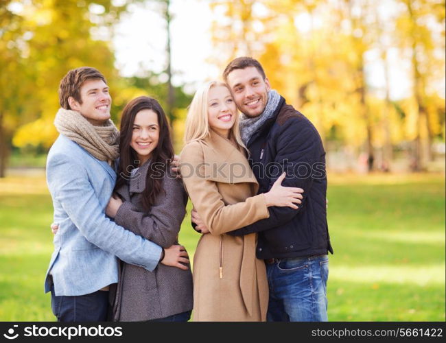 love, relationship, season, friendship and people concept - group of smiling men and women hugging in autumn park