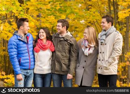 love, relationship, season, friendship and people concept - group of smiling men and women hugging in autumn park
