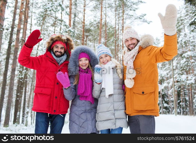 love, relationship, season, friendship and people concept - group of smiling men and women waving hands in winter forest