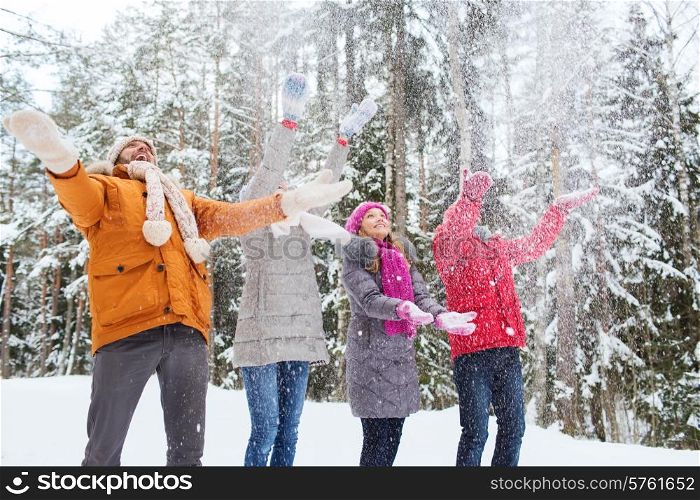 love, relationship, season, friendship and people concept - group of smiling men and women having fun and playing with snow in winter forest